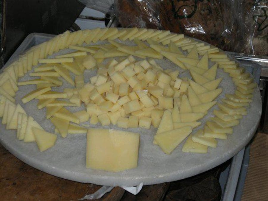 pieces of 'Vasilas Dairy' graviera cheese cutting triangle or cubs on the wood plateau